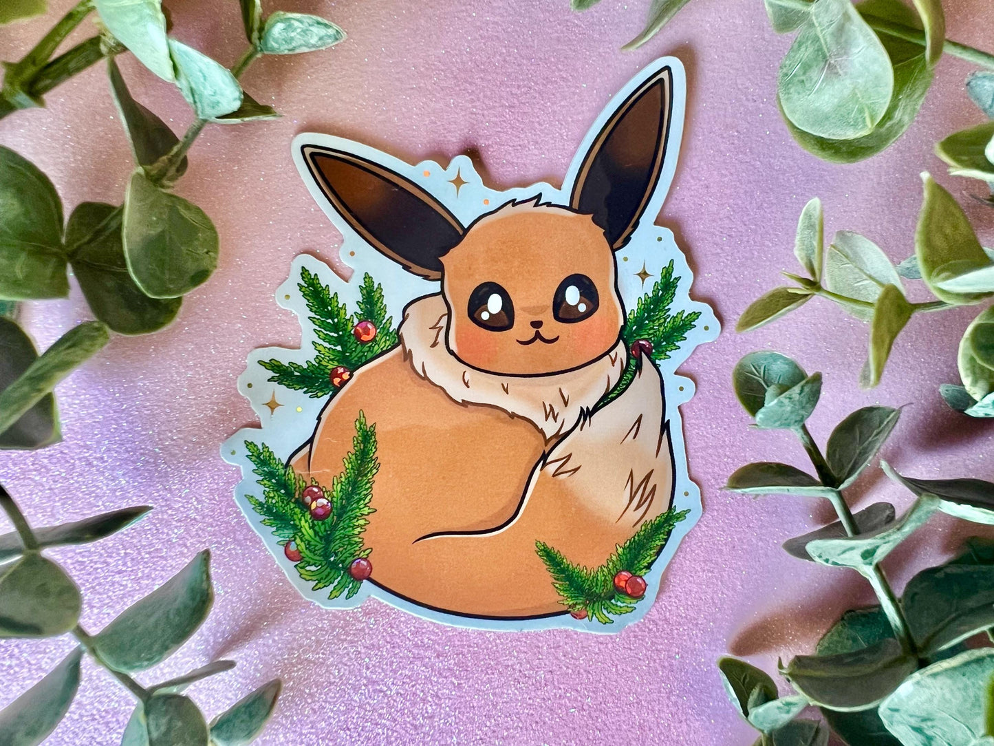 A sticker of a cute brown fox creature with long ears, a fluffy neck and tail, big eyes, surrounded by green leaves and red berries.