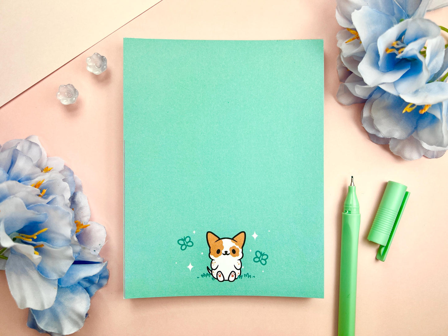 Light blue notepad with an illustration of a cute dog sitting among the butterflies.
