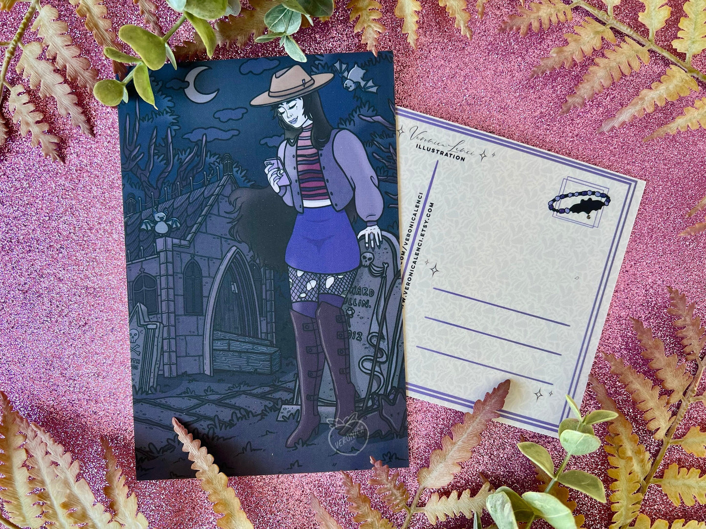 Gothic-style illustration of a vampire in a hat and skirt with a phone on a dark blue/purple background with among gravestones and crypts.