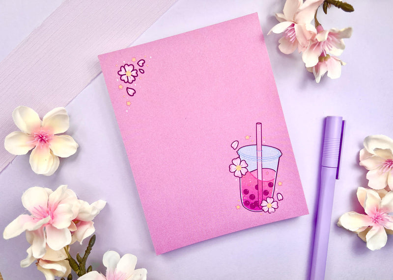 One of our cute 4.25 by 5.5 inch Notepads with a pink milk tea cherry blossom design on it