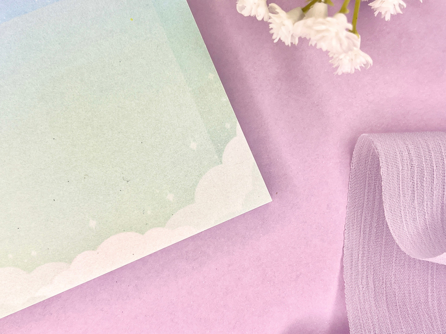 Blue and green sticky notes with clouds bordering the bottom, a faded white square in the middle, and faded sparkles above the clouds.