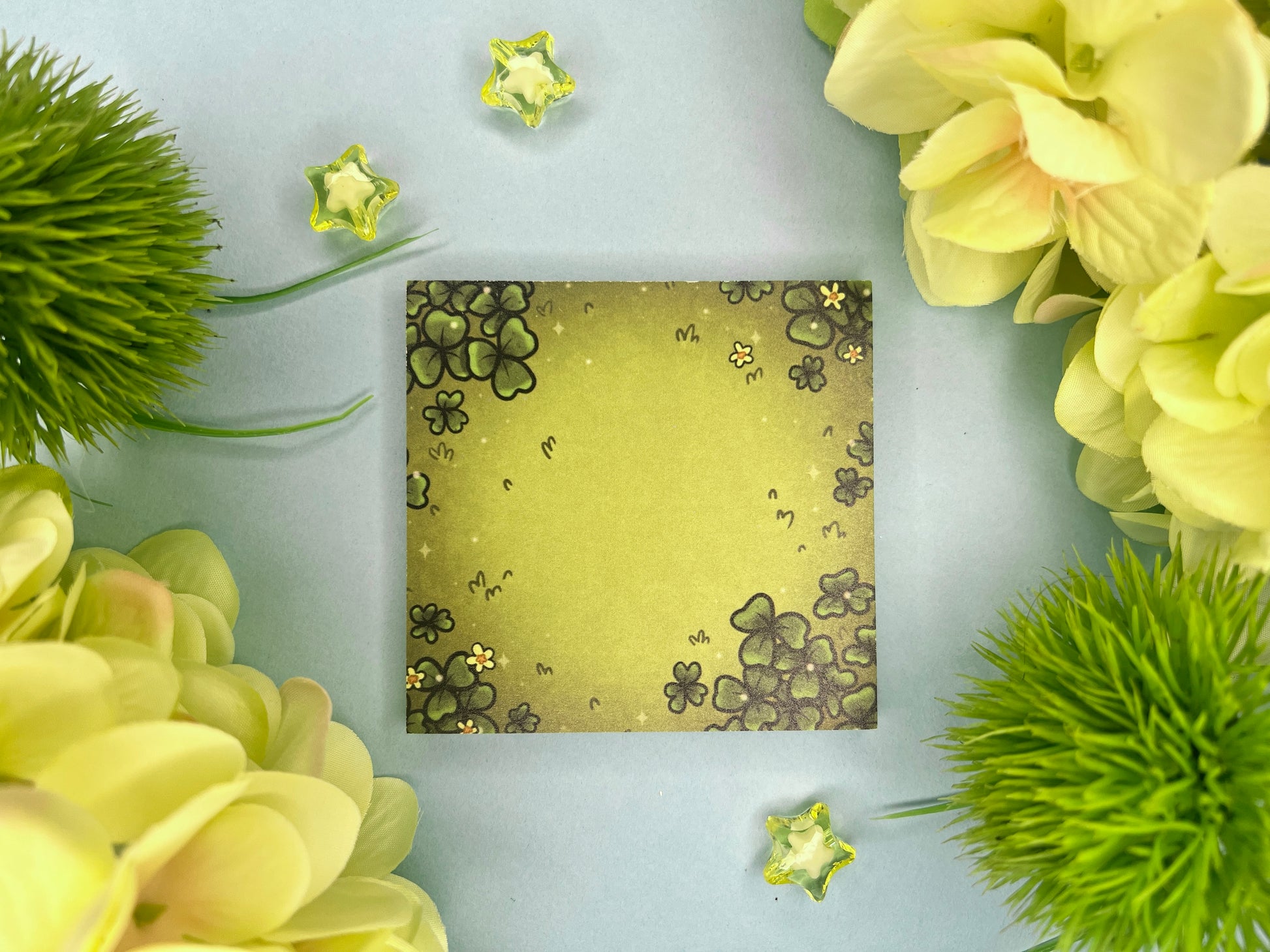 Green sticky notes of a field of green clovers, grass, and yellow flowers.