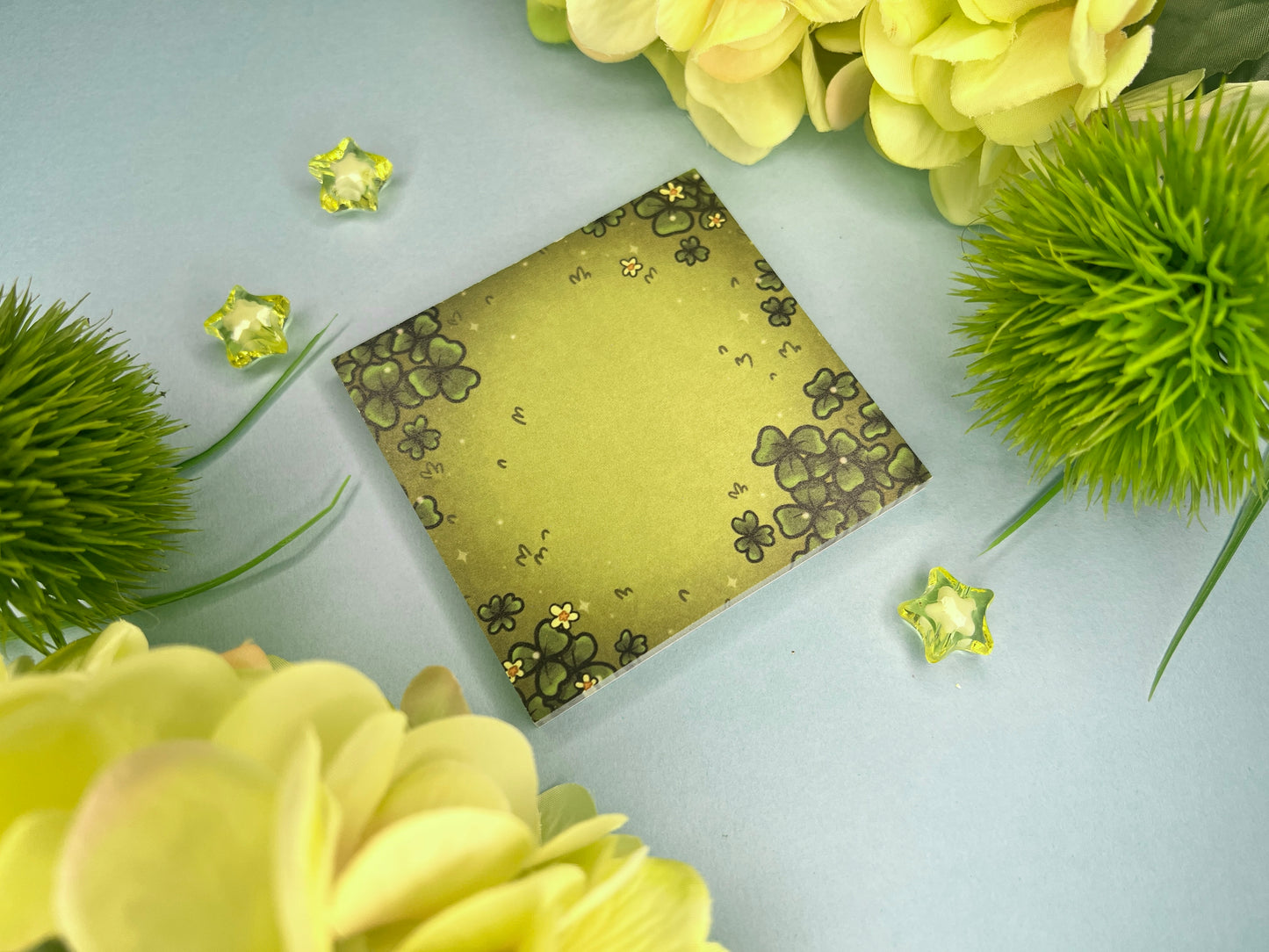 Green sticky notes of a field of green clovers, grass, and yellow flowers.