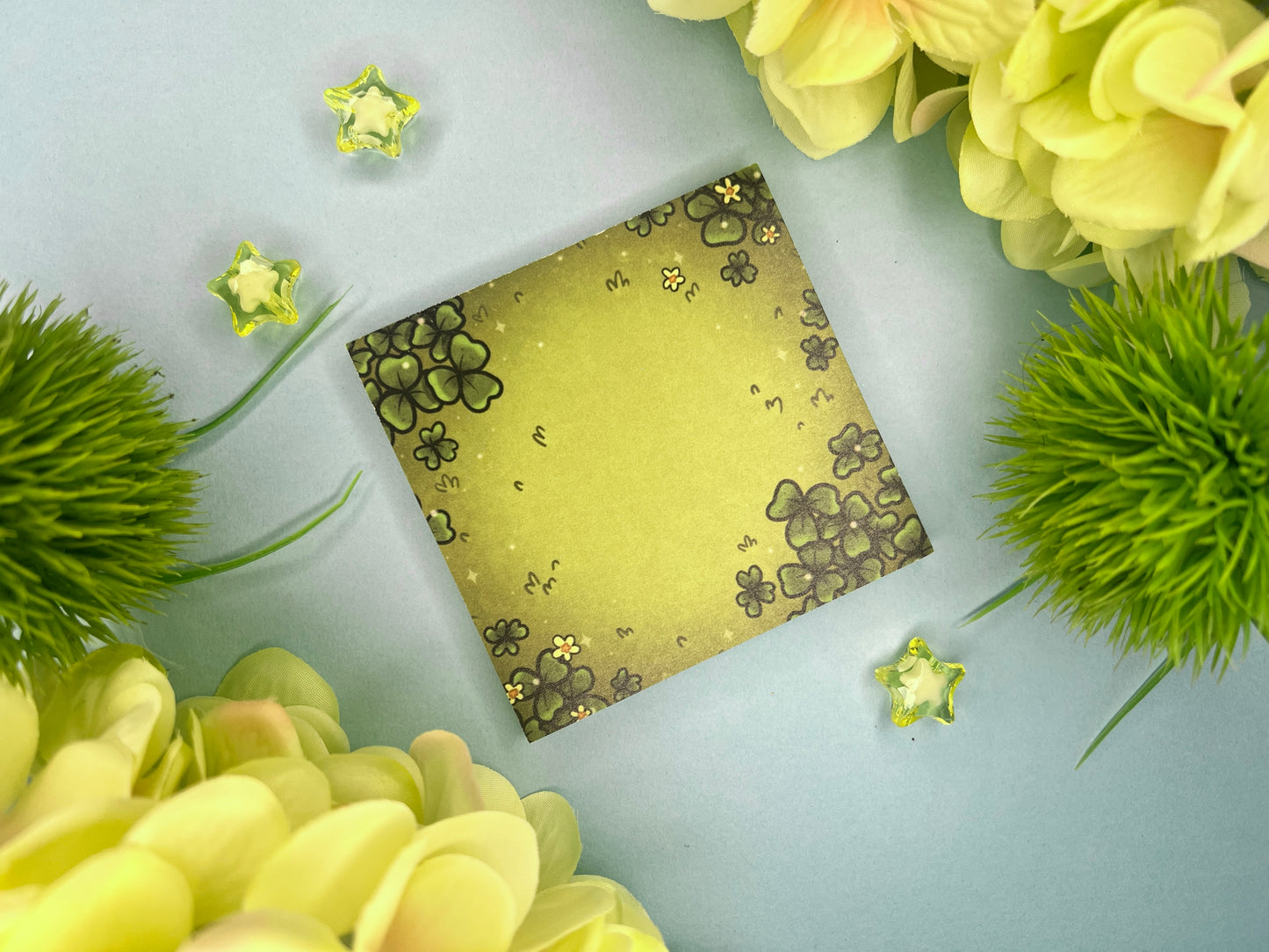 Green sticky notes of a field of green clovers, grass, and yellow flowers.