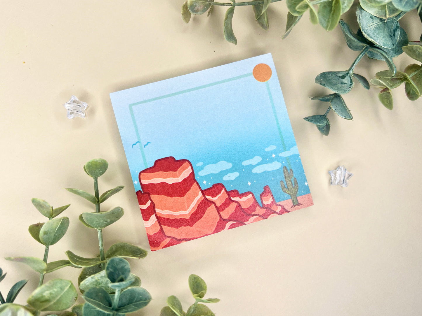 Sticky notes with an illustration of a desert scene with red mountains, a cactus, blue sky, and clouds.