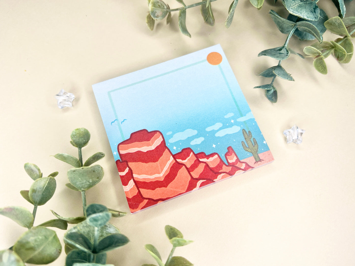 Sticky notes with an illustration of a desert scene with red mountains, a cactus, blue sky, and clouds.