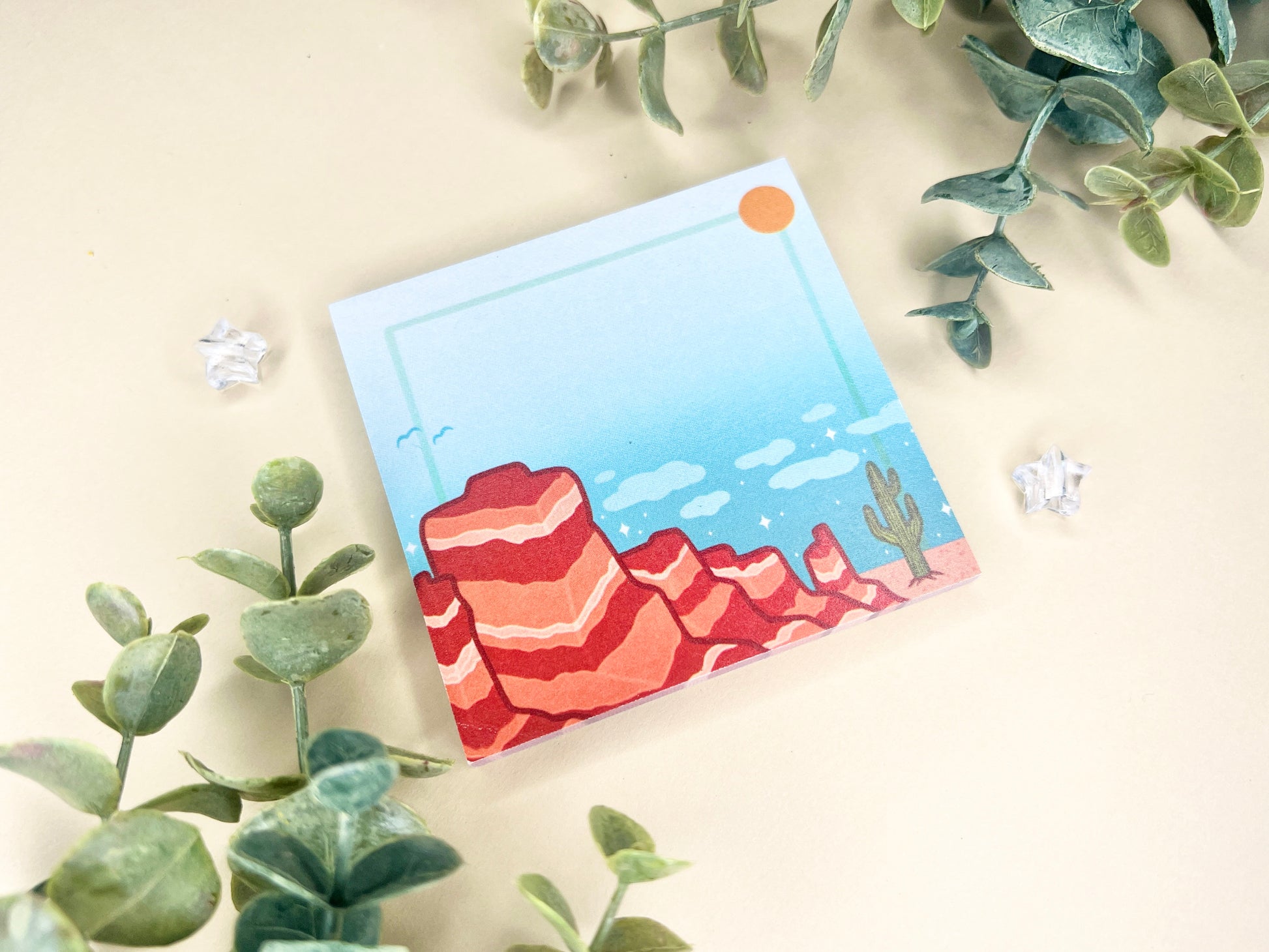 Sticky notes with an illustration of a desert scene with red mountains, a cactus, blue sky, and clouds.