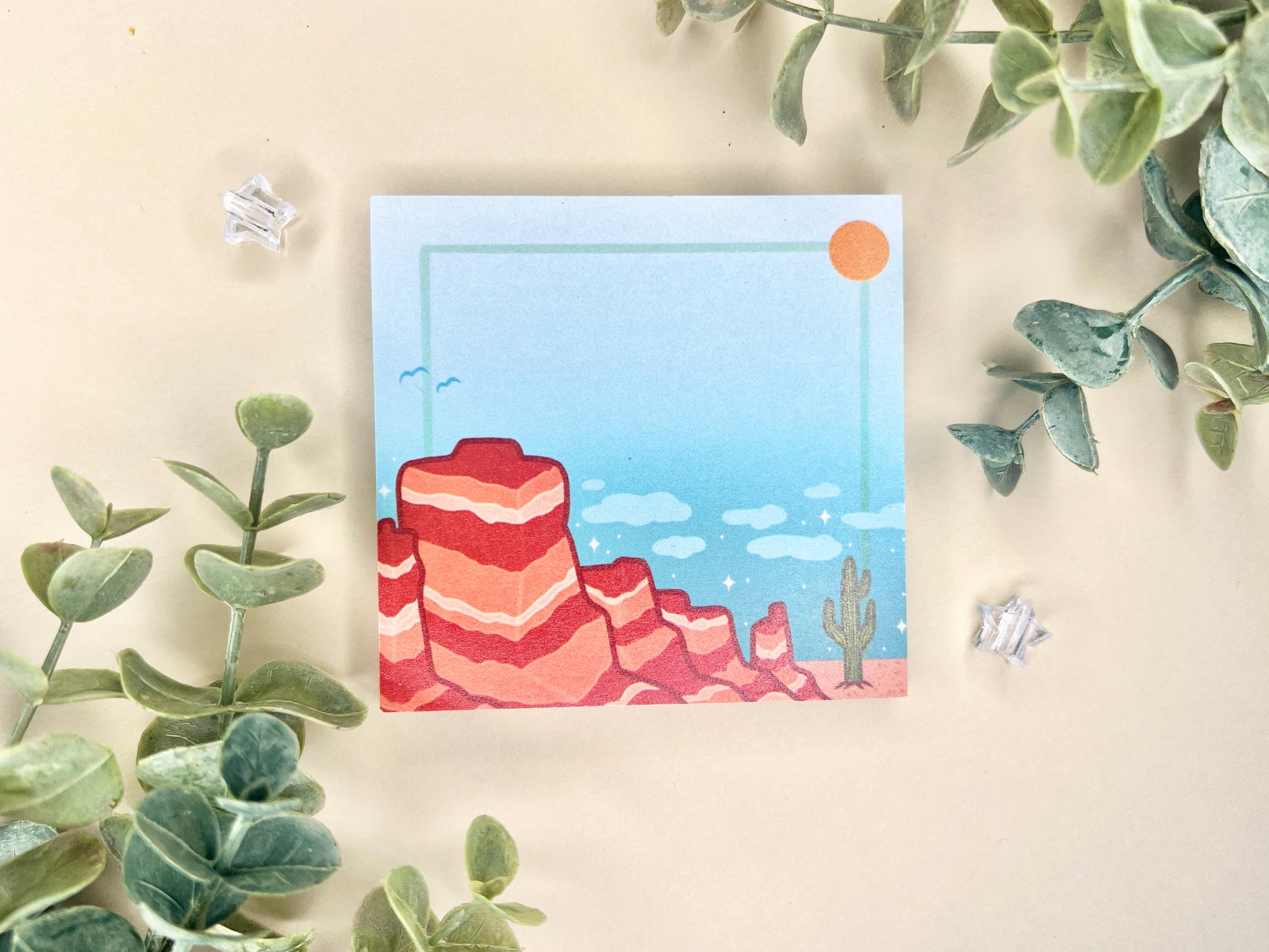 Sticky notes with an illustration of a desert scene with red mountains, a cactus, blue sky, and clouds.