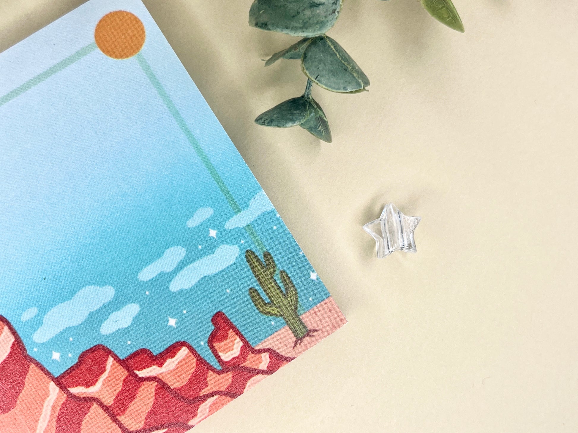 Sticky notes with an illustration of a desert scene with red mountains, a cactus, blue sky, and clouds.