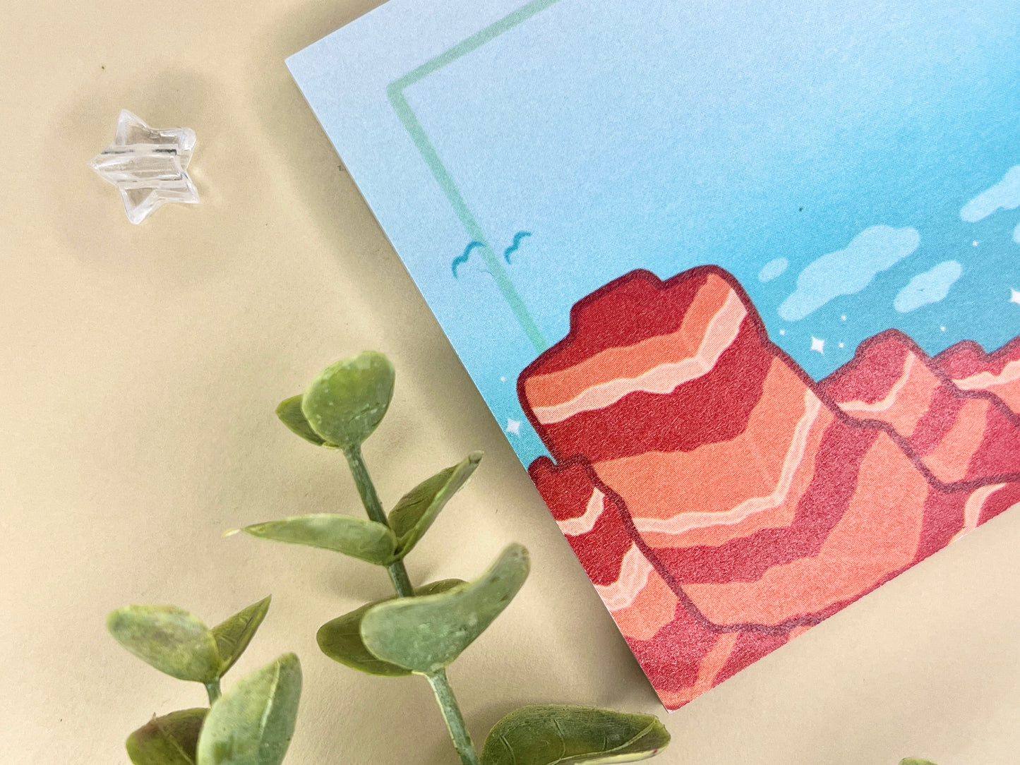 Sticky notes with an illustration of a desert scene with red mountains, a cactus, blue sky, and clouds.