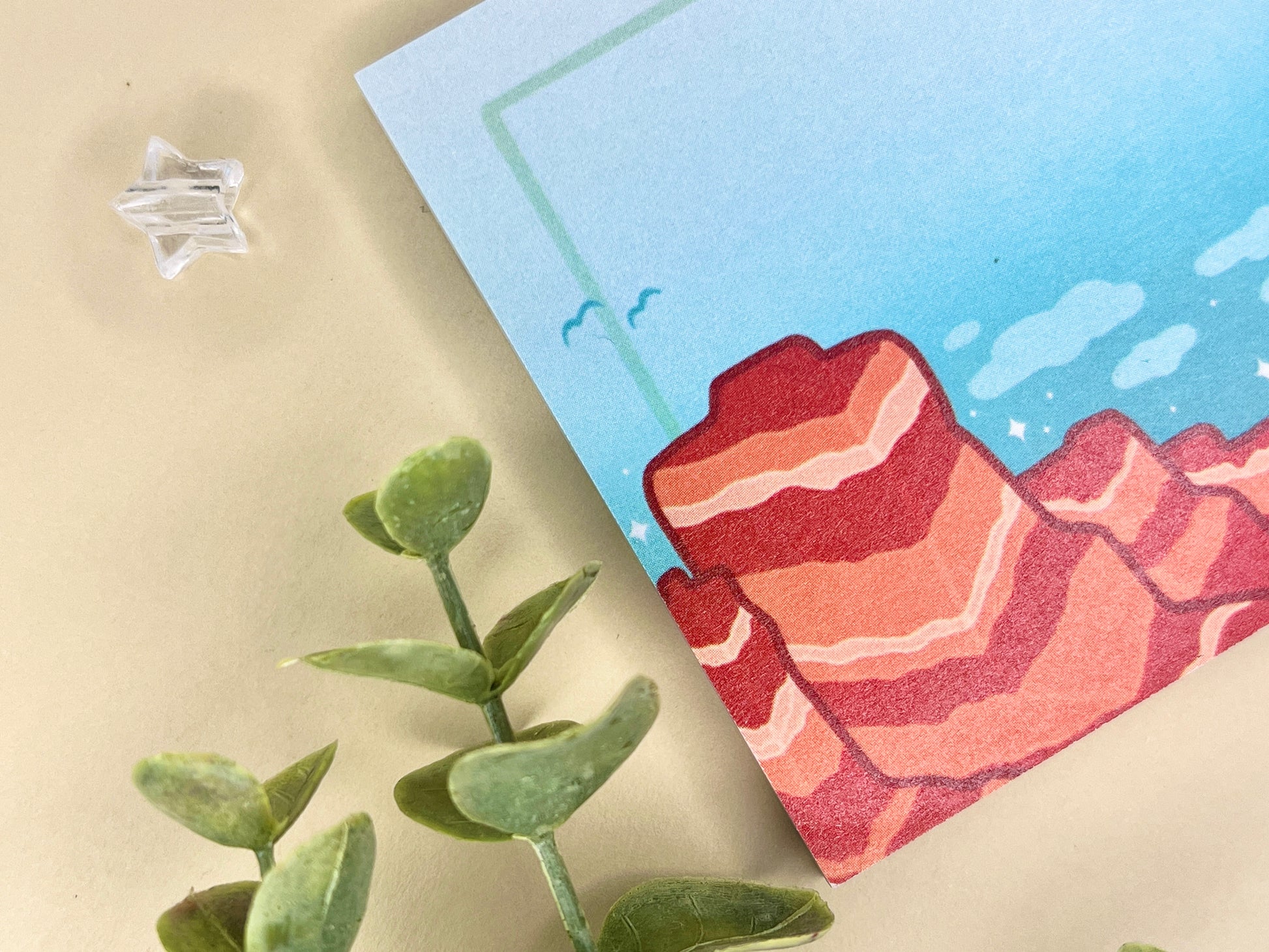 Sticky notes with an illustration of a desert scene with red mountains, a cactus, blue sky, and clouds.