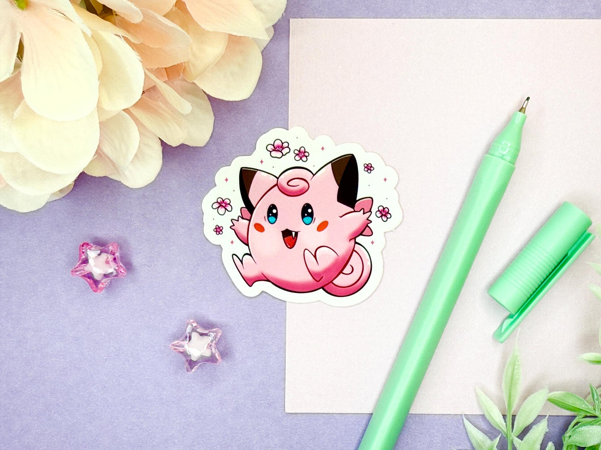 Cute pink animal fairy sticker with brown tipped ears and blue eyes surrounded by pink flowers.