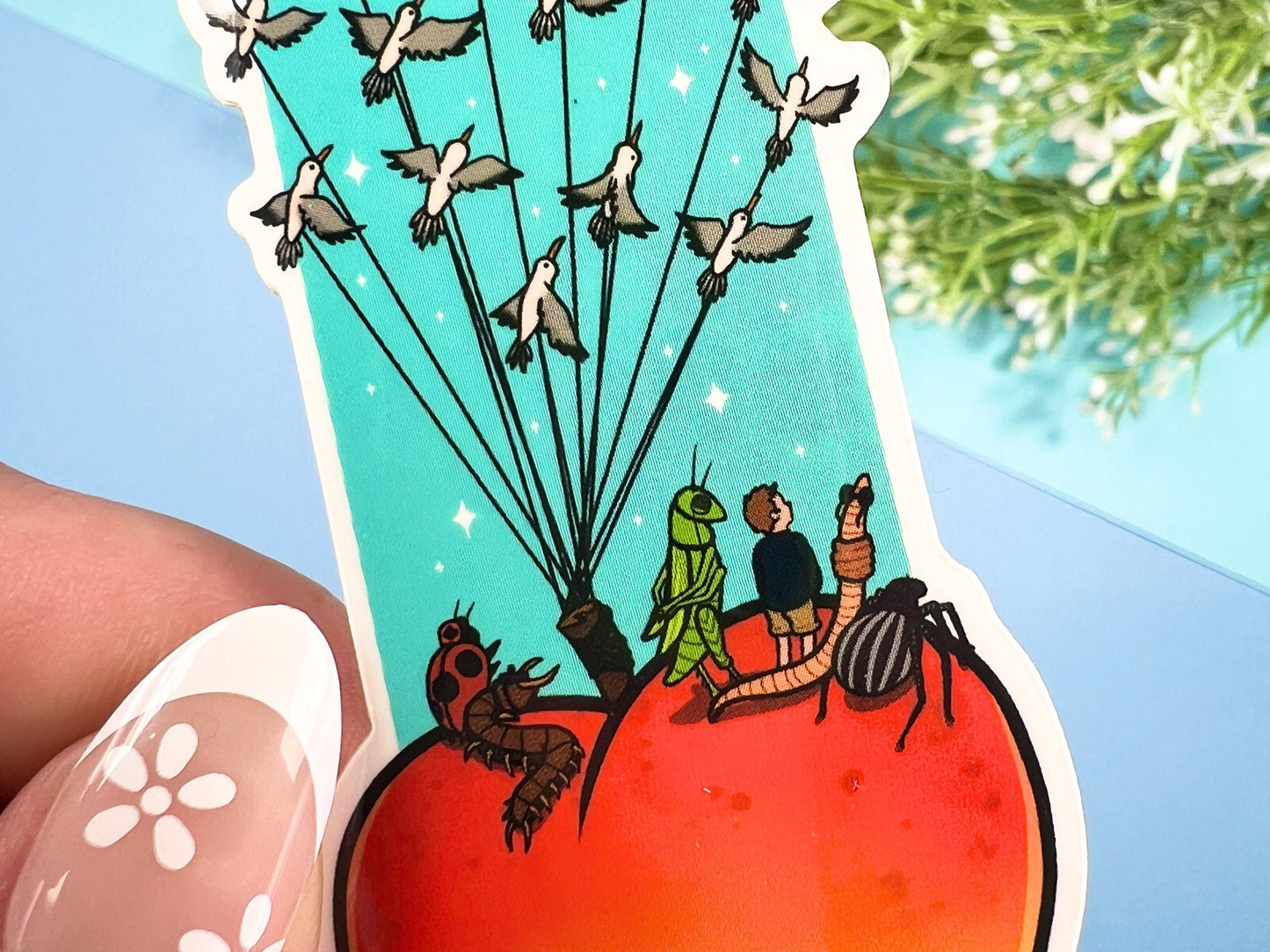 Sticker of a giant peach with people and bugs being carried by birds on a colorful blue background.
