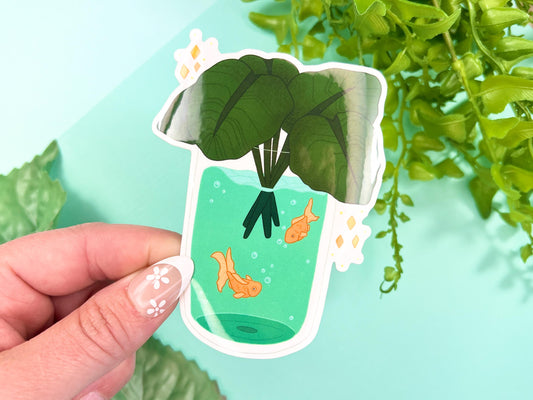 A vase filled with Calathea leaves and has water with Goldfish inside.