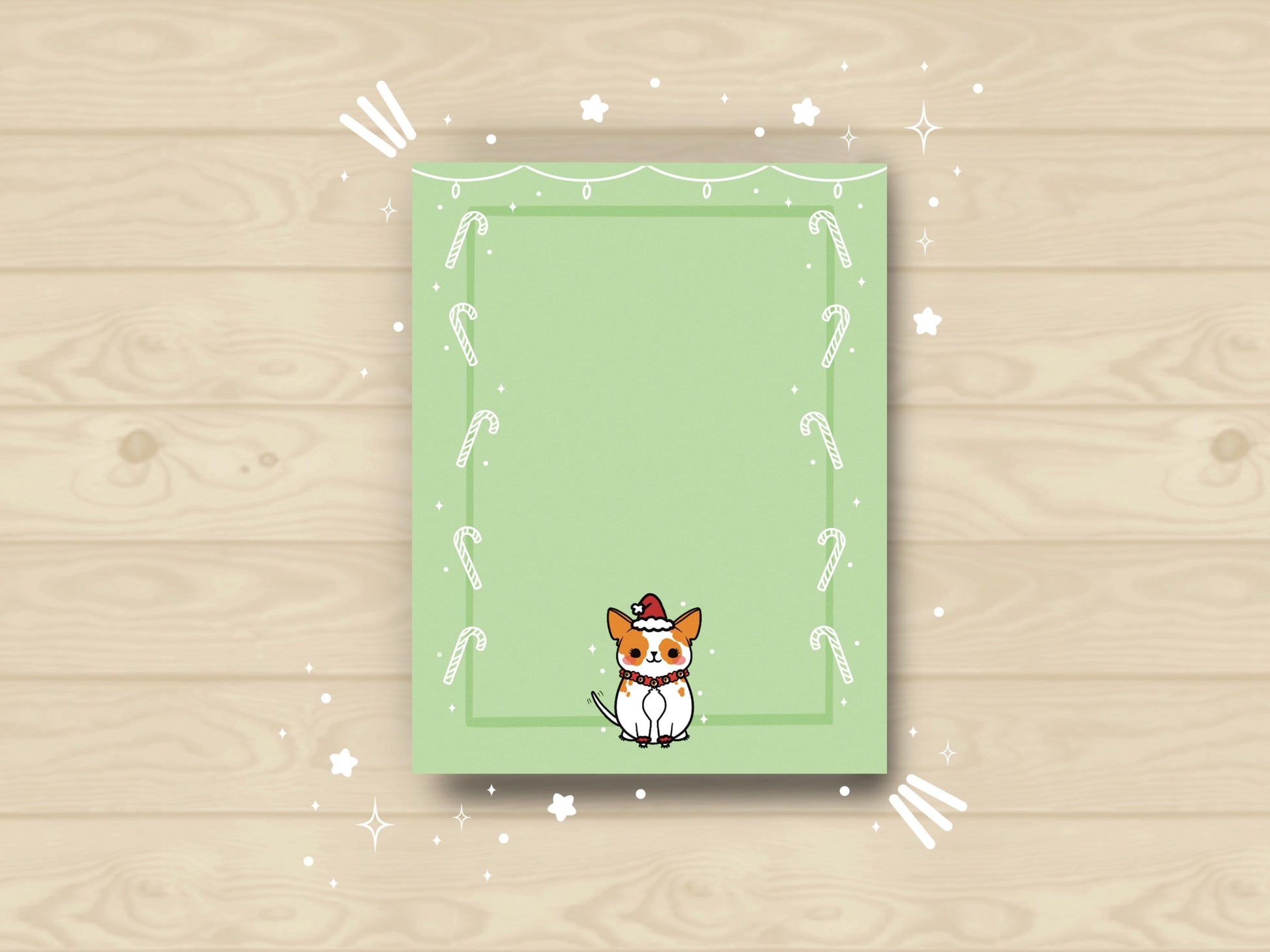 A green notepad that has an illustration of a cute dog dressed up in a Santa hat and bells and has a green and white candy cane border around it.