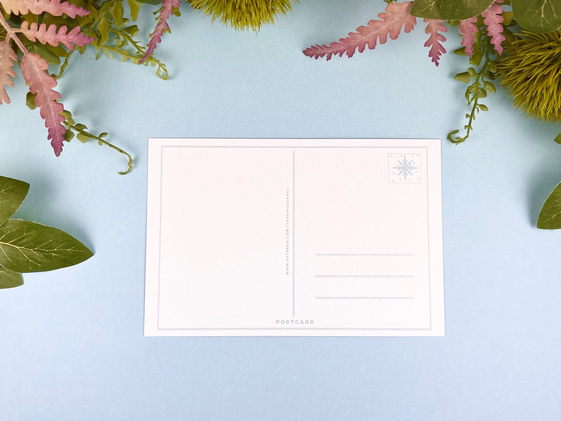 Back of the postcard with a line down the middle, lines on the right side for and address, and a cute snowflake illustration where the stamp would go. 