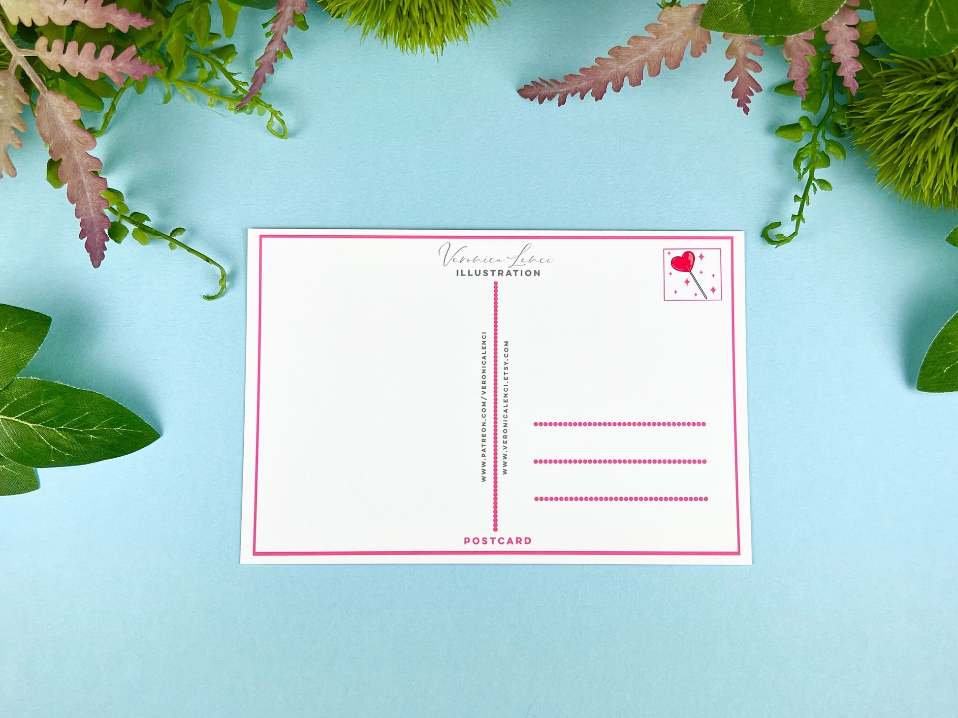 Back of the postcard with a line down the middle, lines on the right side for and address, and a cute heart lollipop illustration where the stamp would go. 