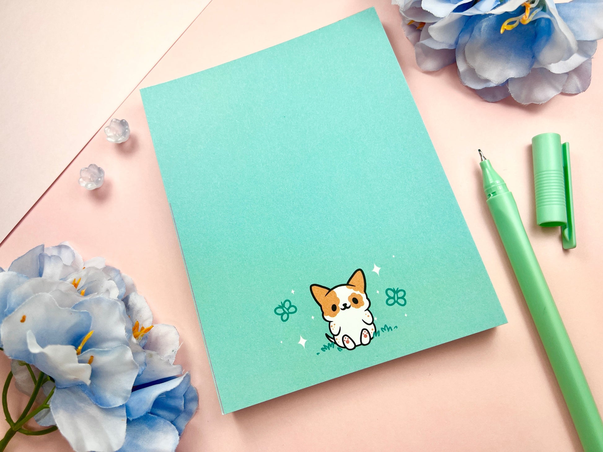Light blue notepad with an illustration of a cute dog sitting among the butterflies.