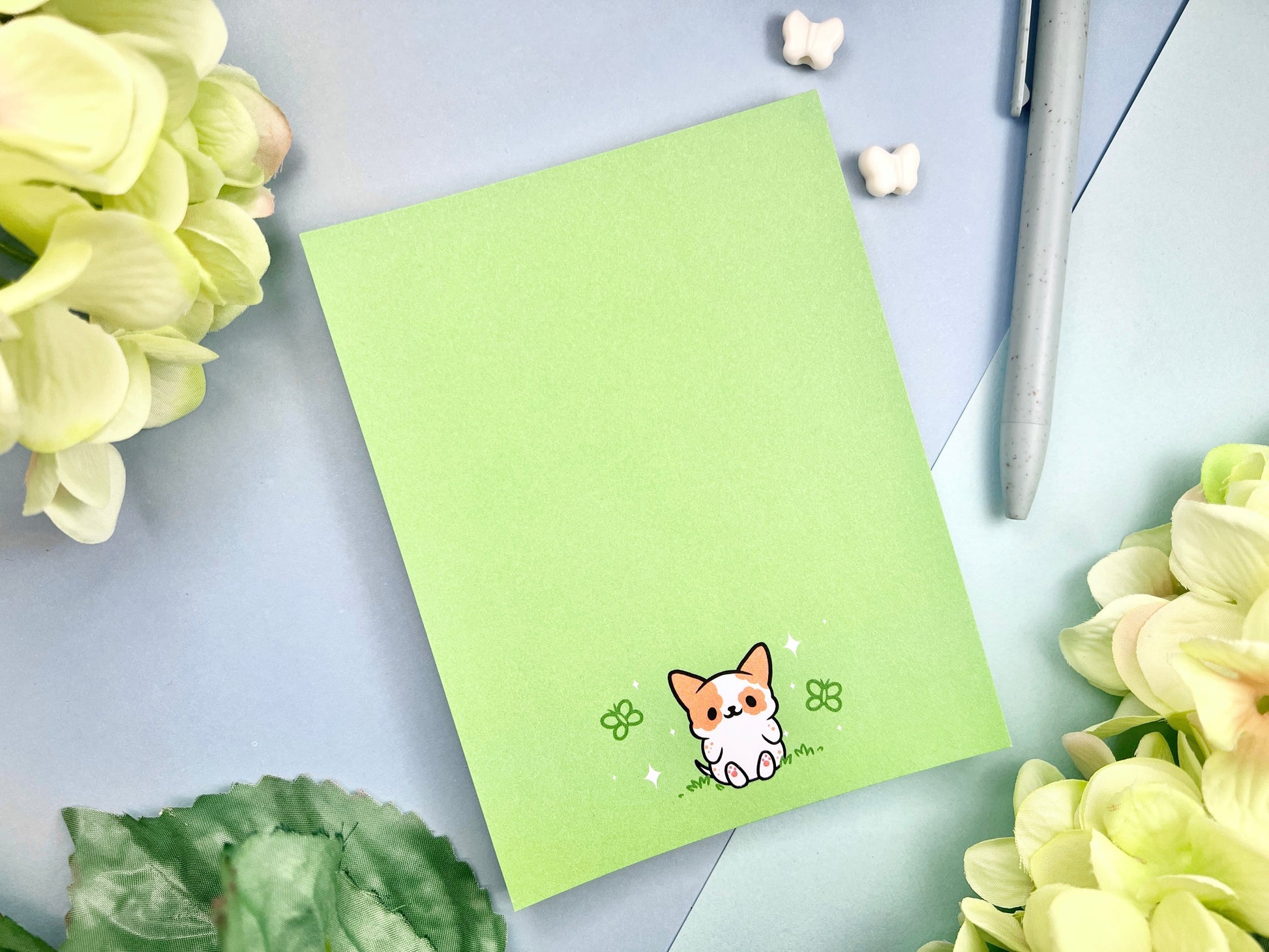 Light green notepad with an illustration of a cute dog sitting among the butterflies.