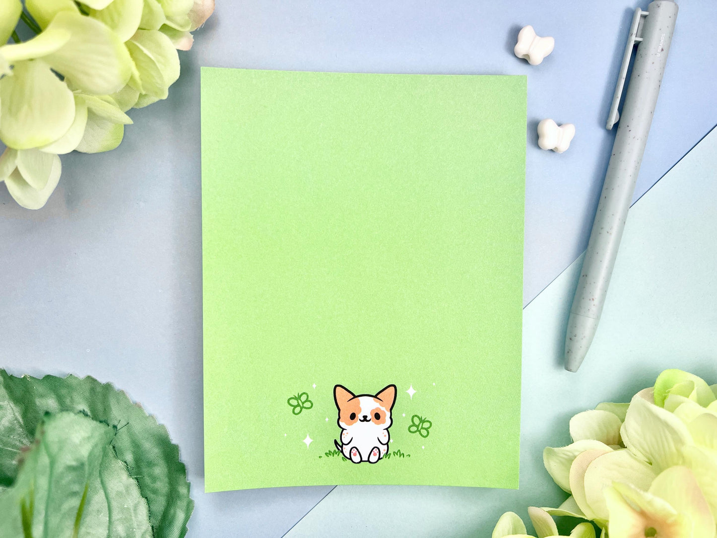 Light green notepad with an illustration of a cute dog sitting among the butterflies.