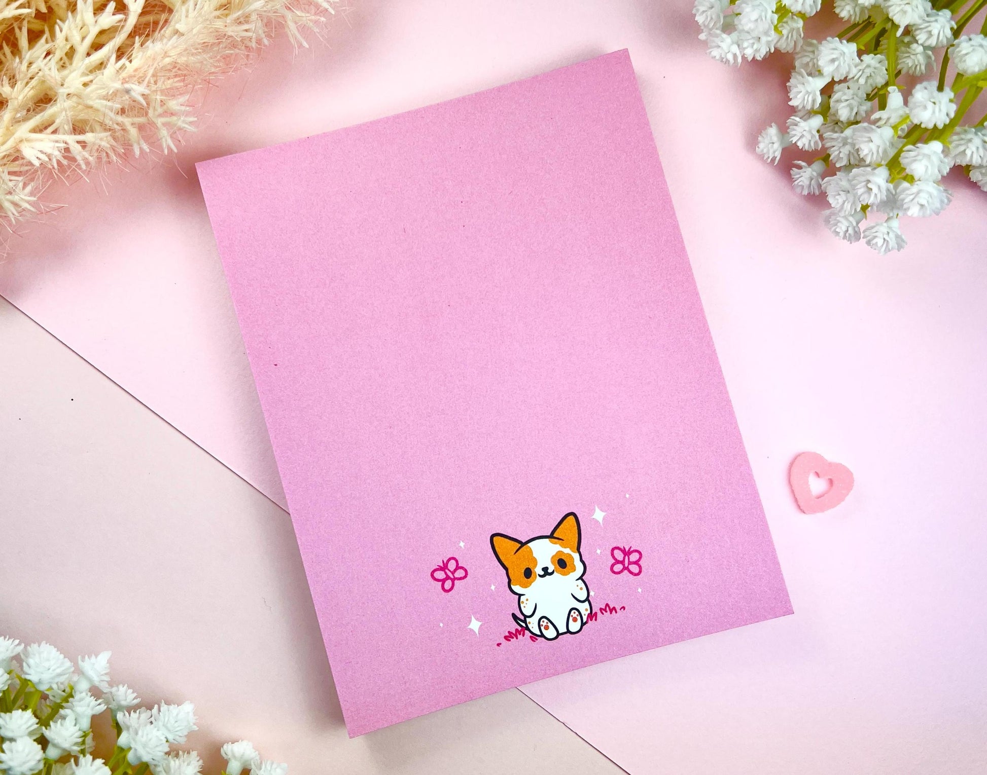 Pink notepad with an illustration of a cute dog sitting among the butterflies.