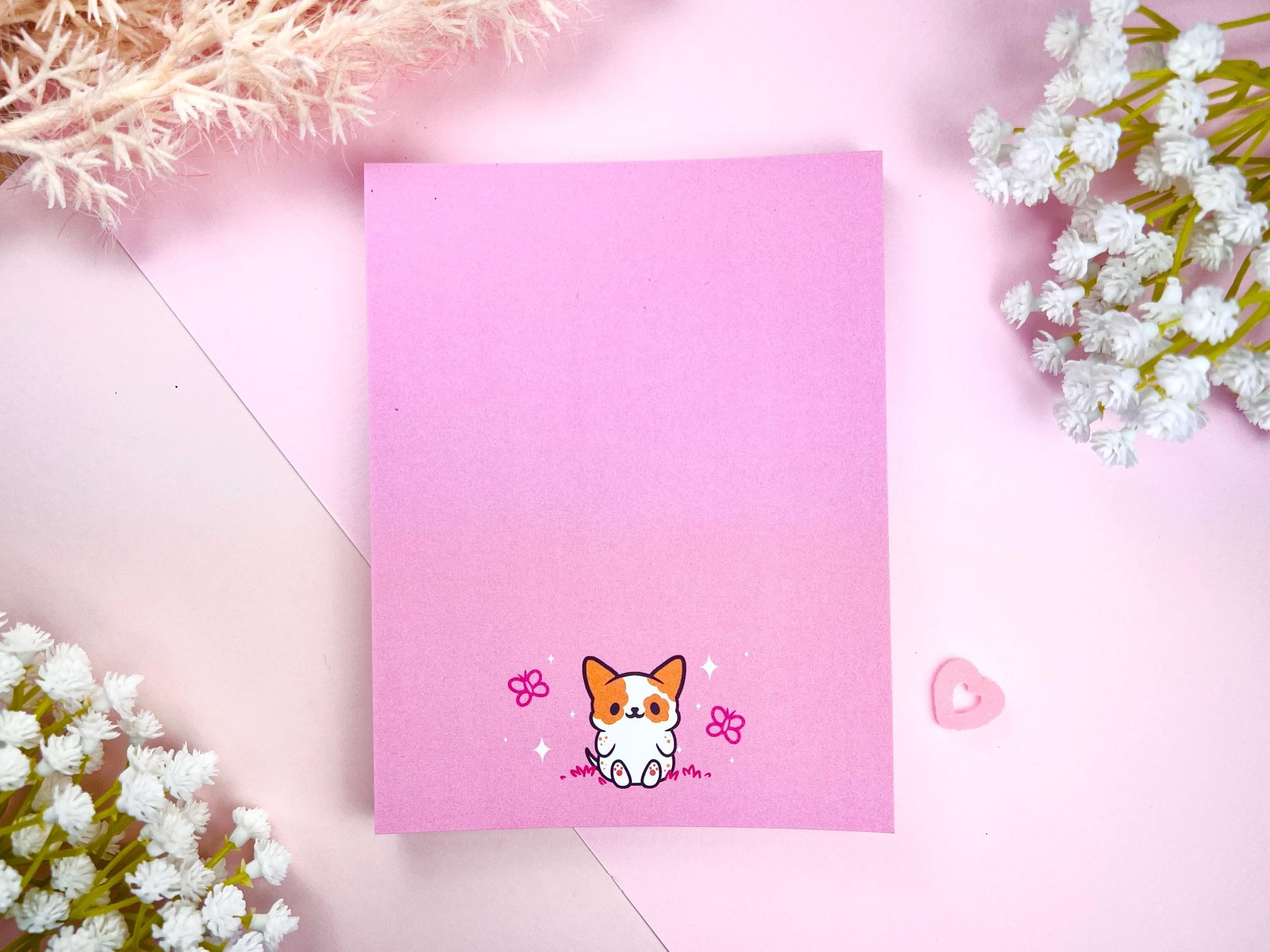 Pink notepad with an illustration of a cute dog sitting among the butterflies.