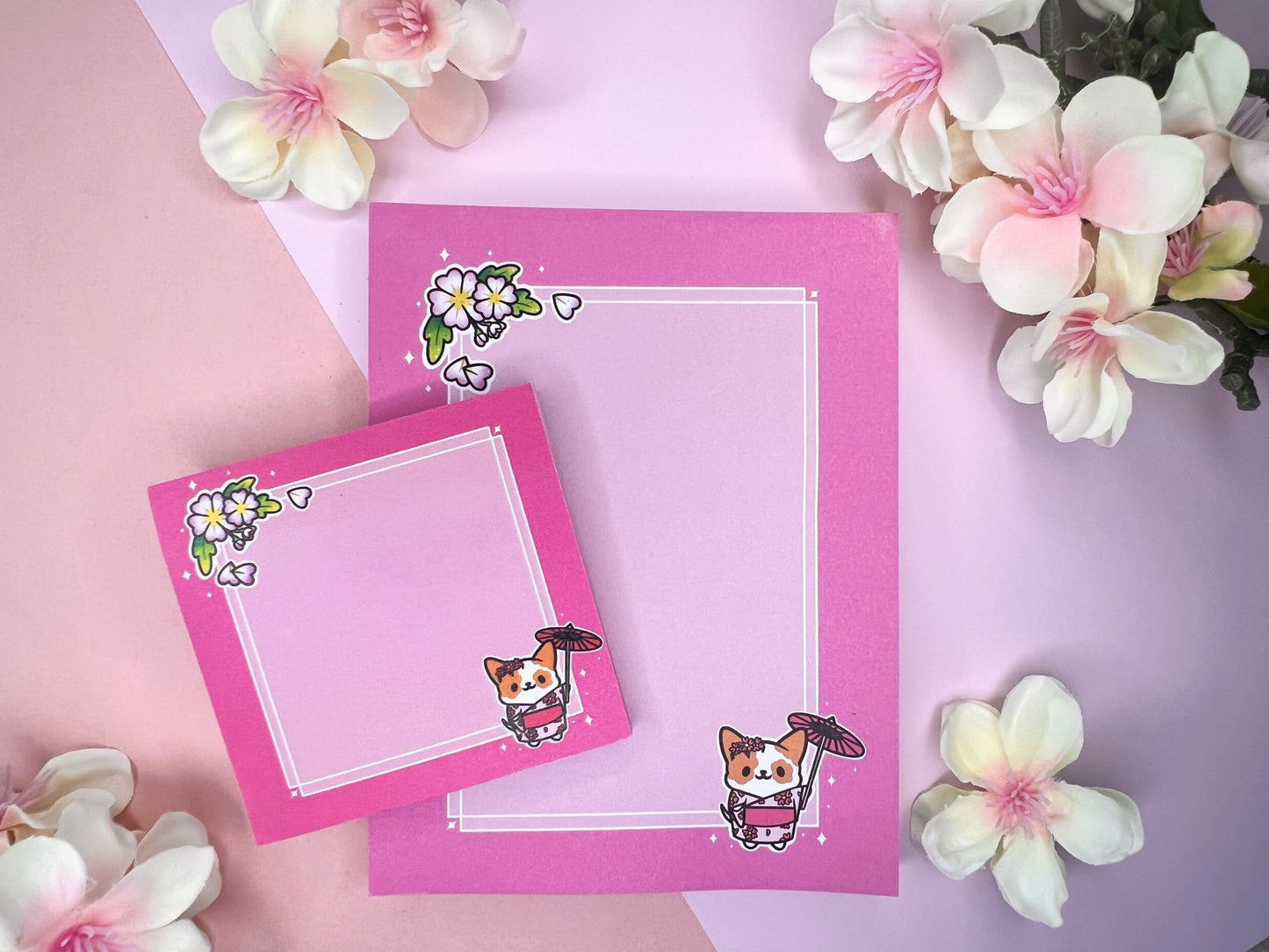 A pink gift set, including sticky notes and a notepad, that has an illustration of a cute dog wearing a pink kimono holding an umbrella under cherry blossoms. 