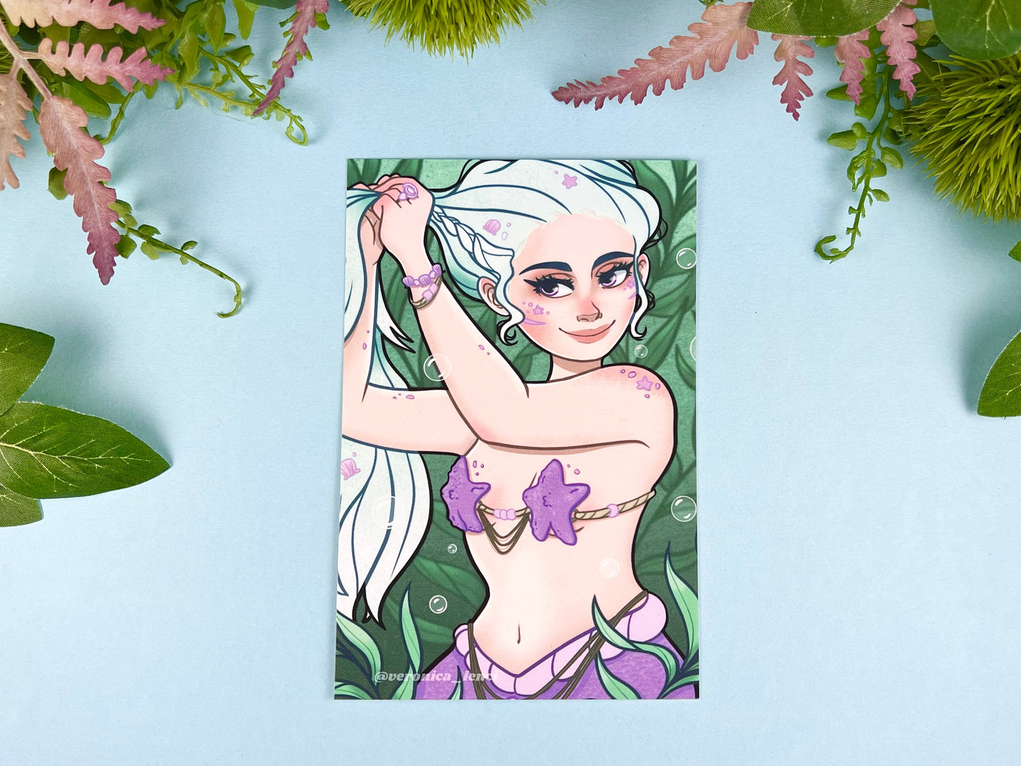 Beautiful mermaid putting her blue hair up and getting ready for her day among the seaweed.