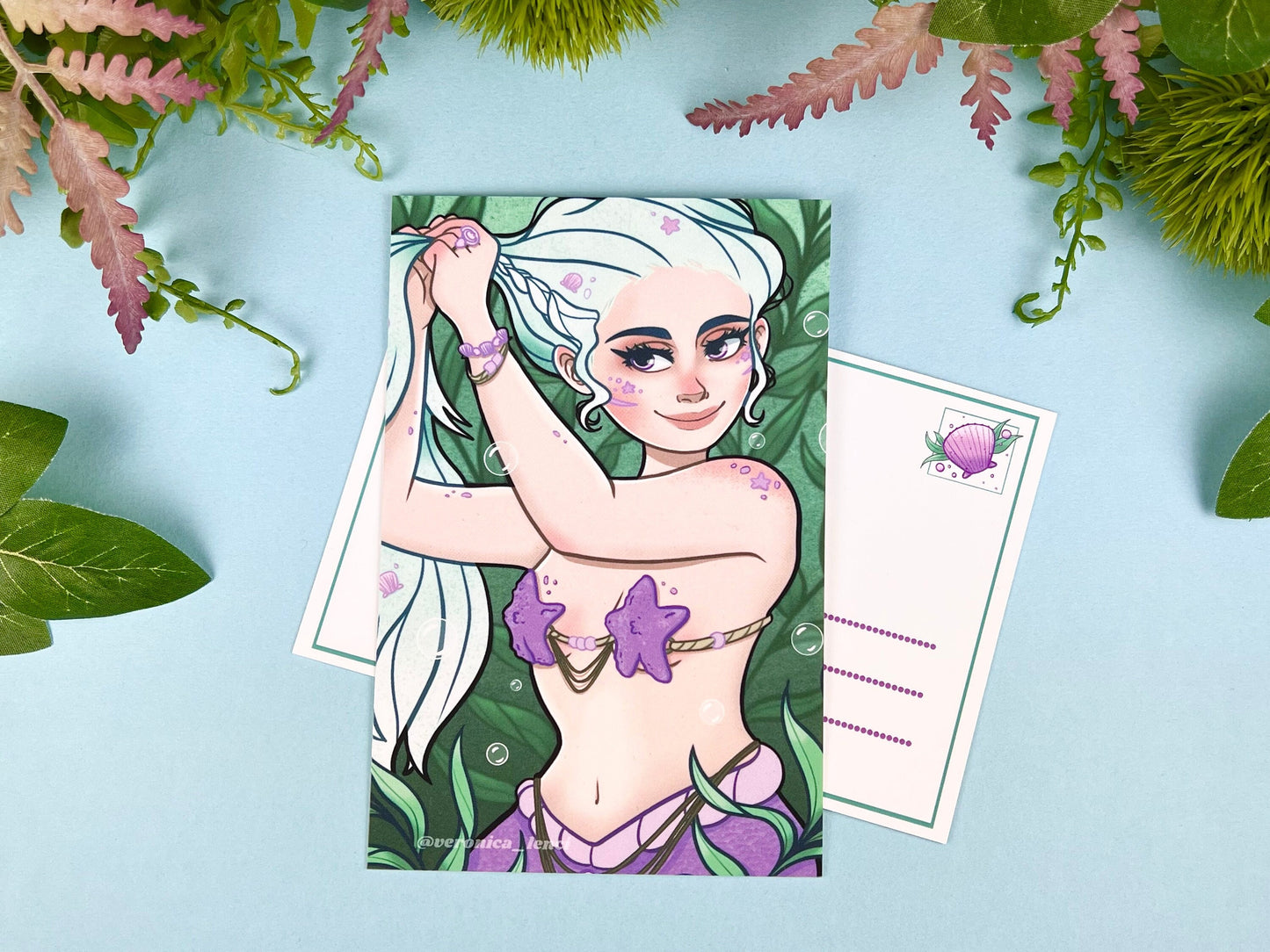 Beautiful mermaid putting her blue hair up and getting ready for her day among the seaweed.