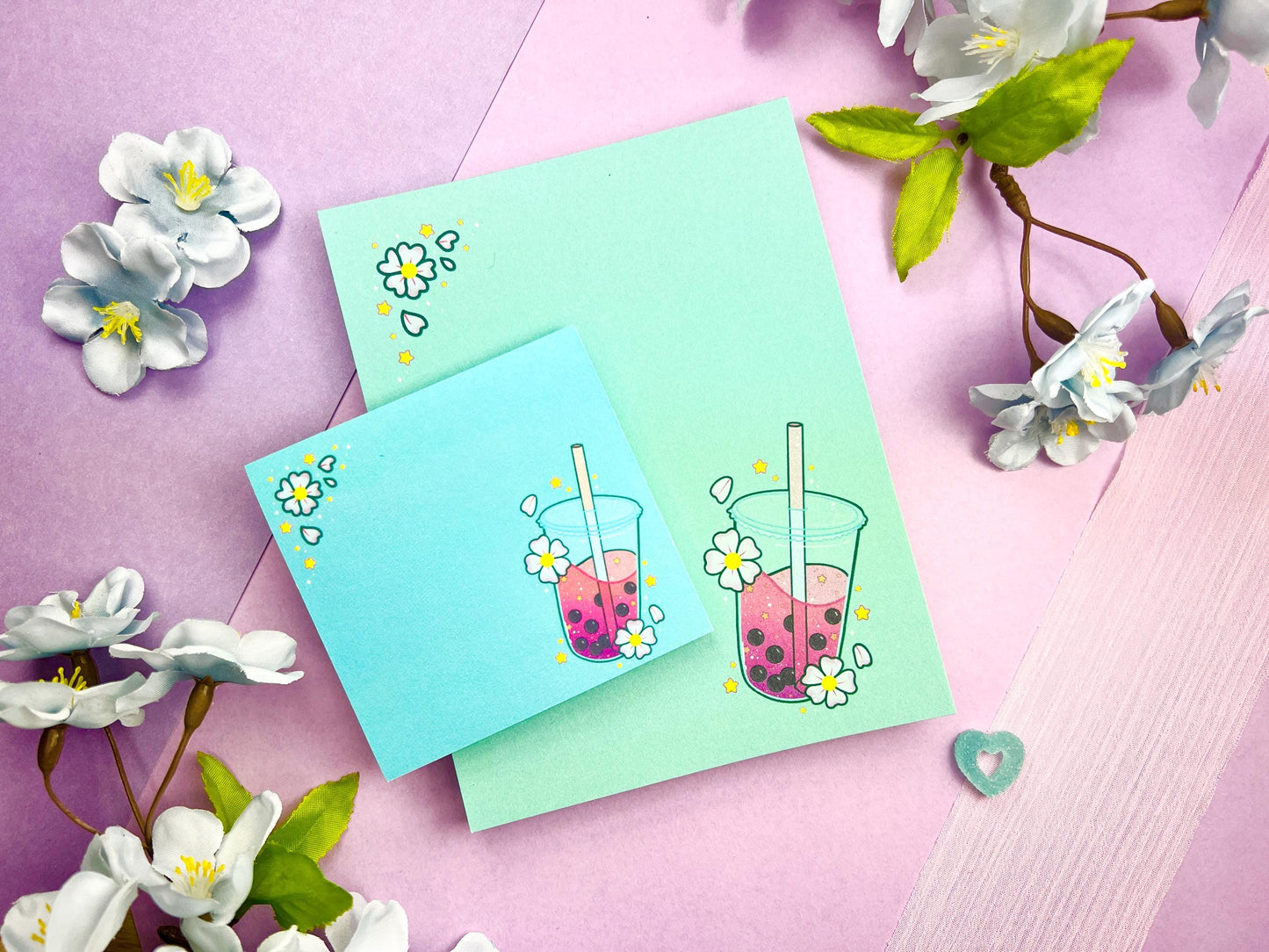 A light blue gift set including one sticky note and one notepad with an illustration of pink boba milk tea surrounded by pink flowers and yellow stars.