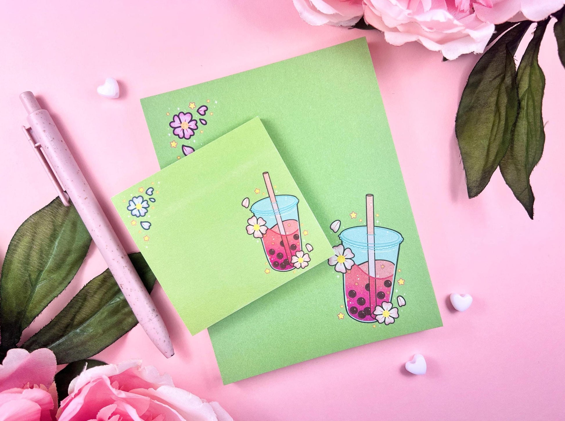 A green gift set including one sticky note and one notepad with an illustration of pink boba milk tea surrounded by pink flowers and yellow stars.