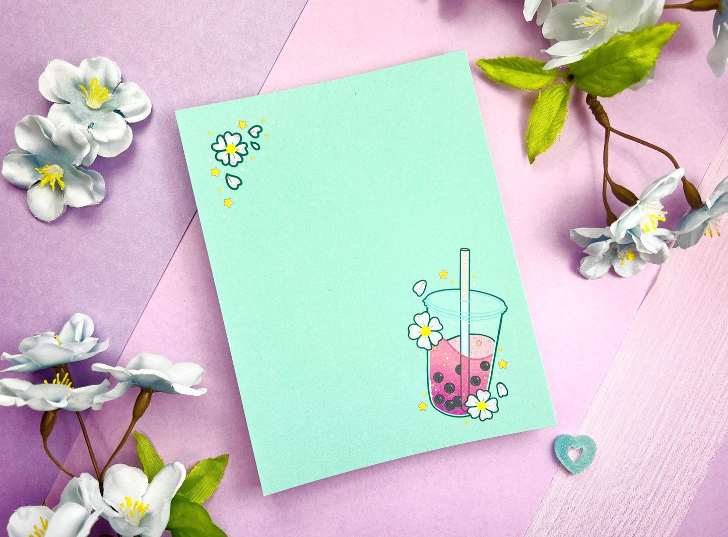 Light blue notepad with an illustration of pink boba milk tea surrounded by pink flowers.