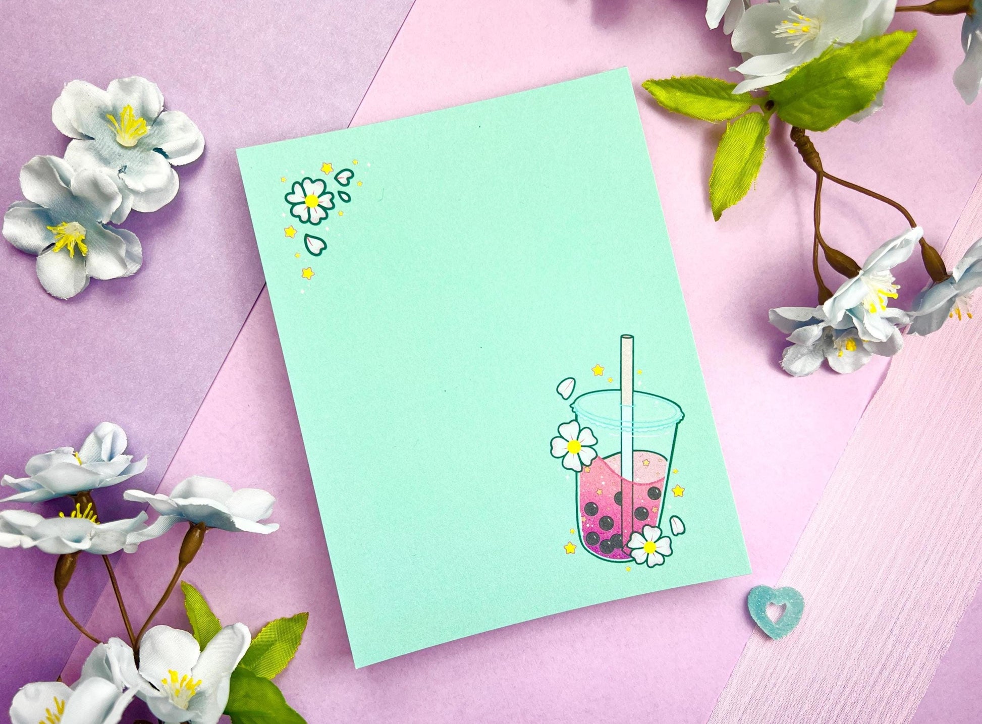 Light blue notepad with an illustration of pink boba milk tea surrounded by pink flowers.