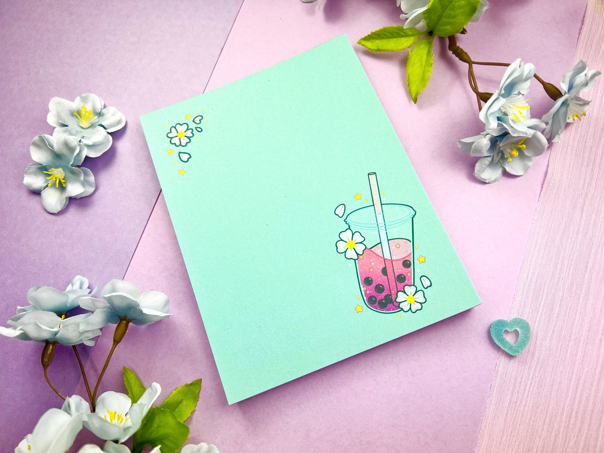 Light blue notepad with an illustration of pink boba milk tea surrounded by pink flowers.