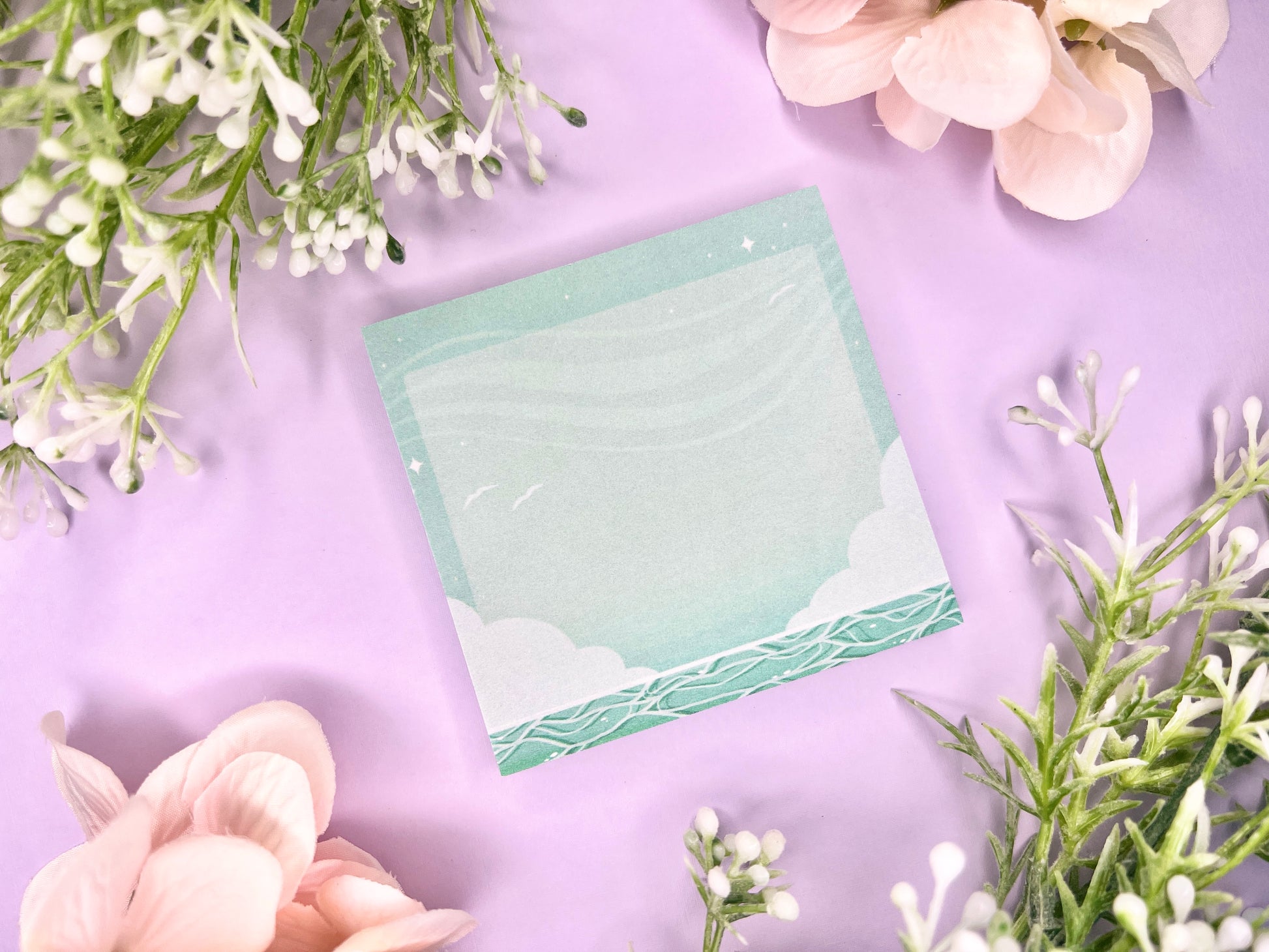 Green and white sticky notes with an illustration of an ocean below the clouds.