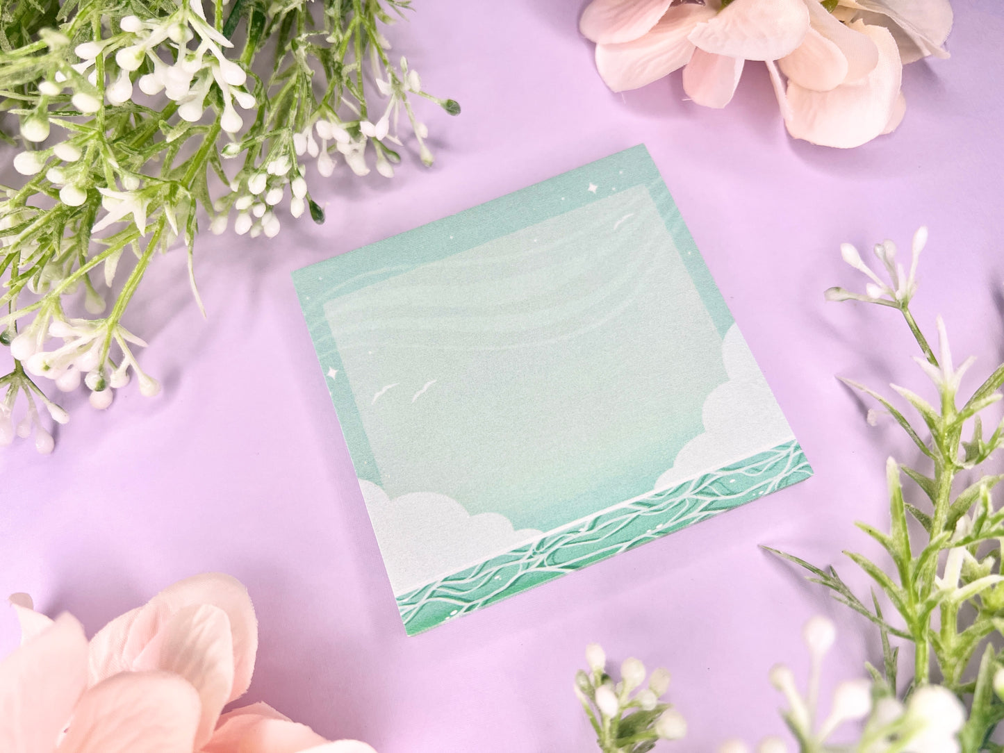 Green and white sticky notes with an illustration of an ocean below the clouds.