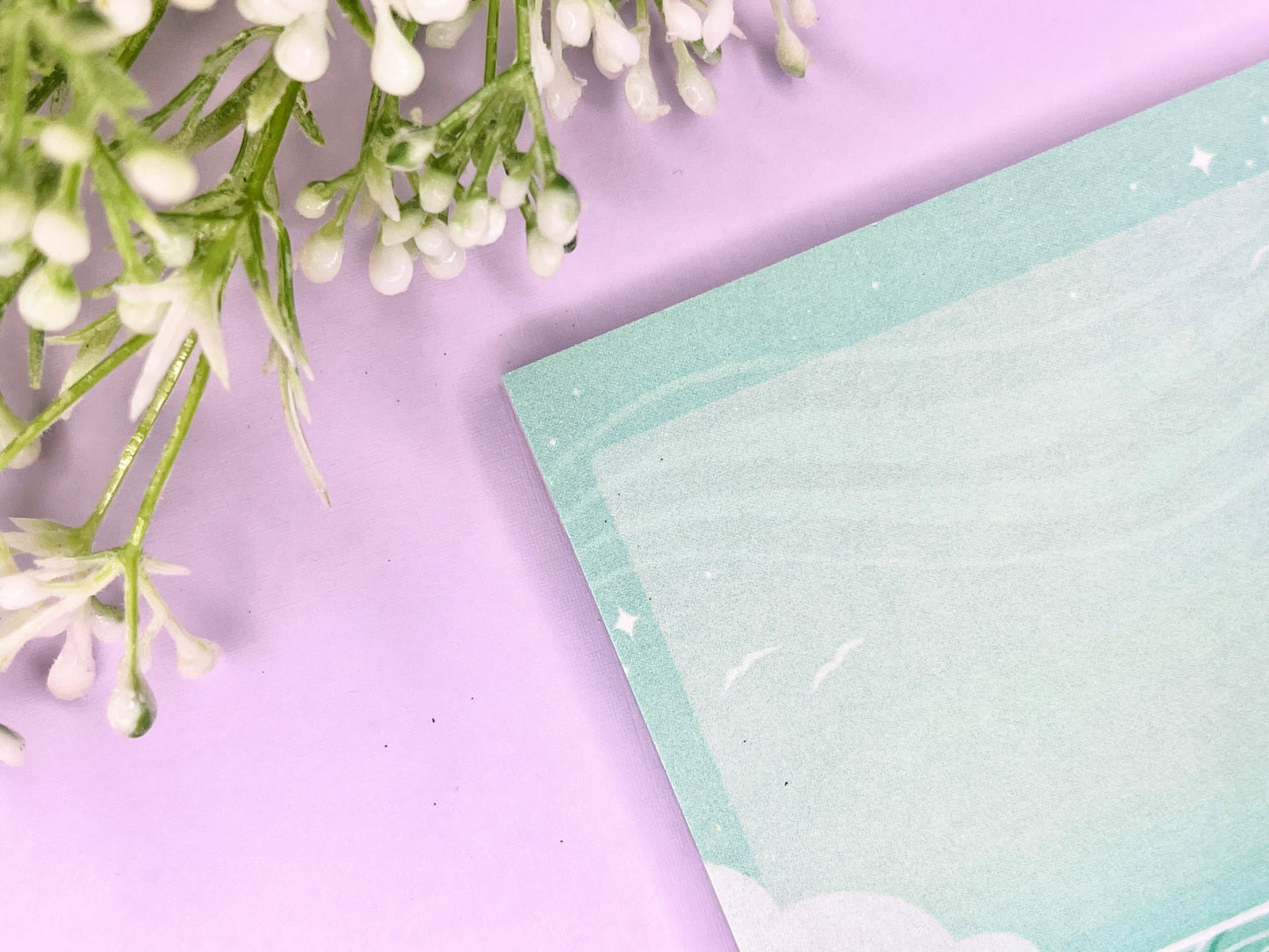 Green and white sticky notes with an illustration of an ocean below the clouds.