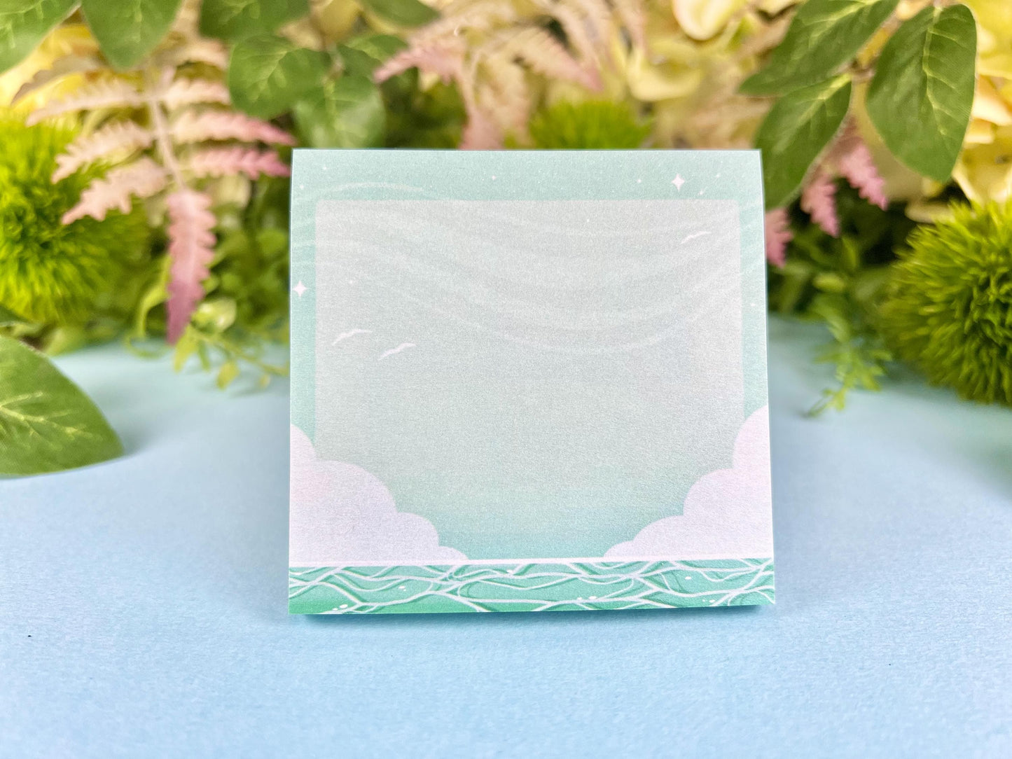 Green and white sticky notes with an illustration of an ocean below the clouds.