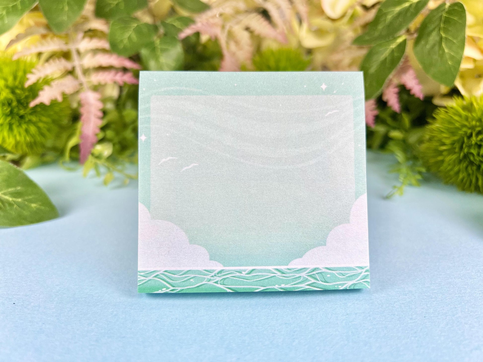 Green and white sticky notes with an illustration of an ocean below the clouds.