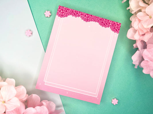 Pink notepad with pink hydrangea flowers bordering the top and a double white border inset from the sides and bottom.