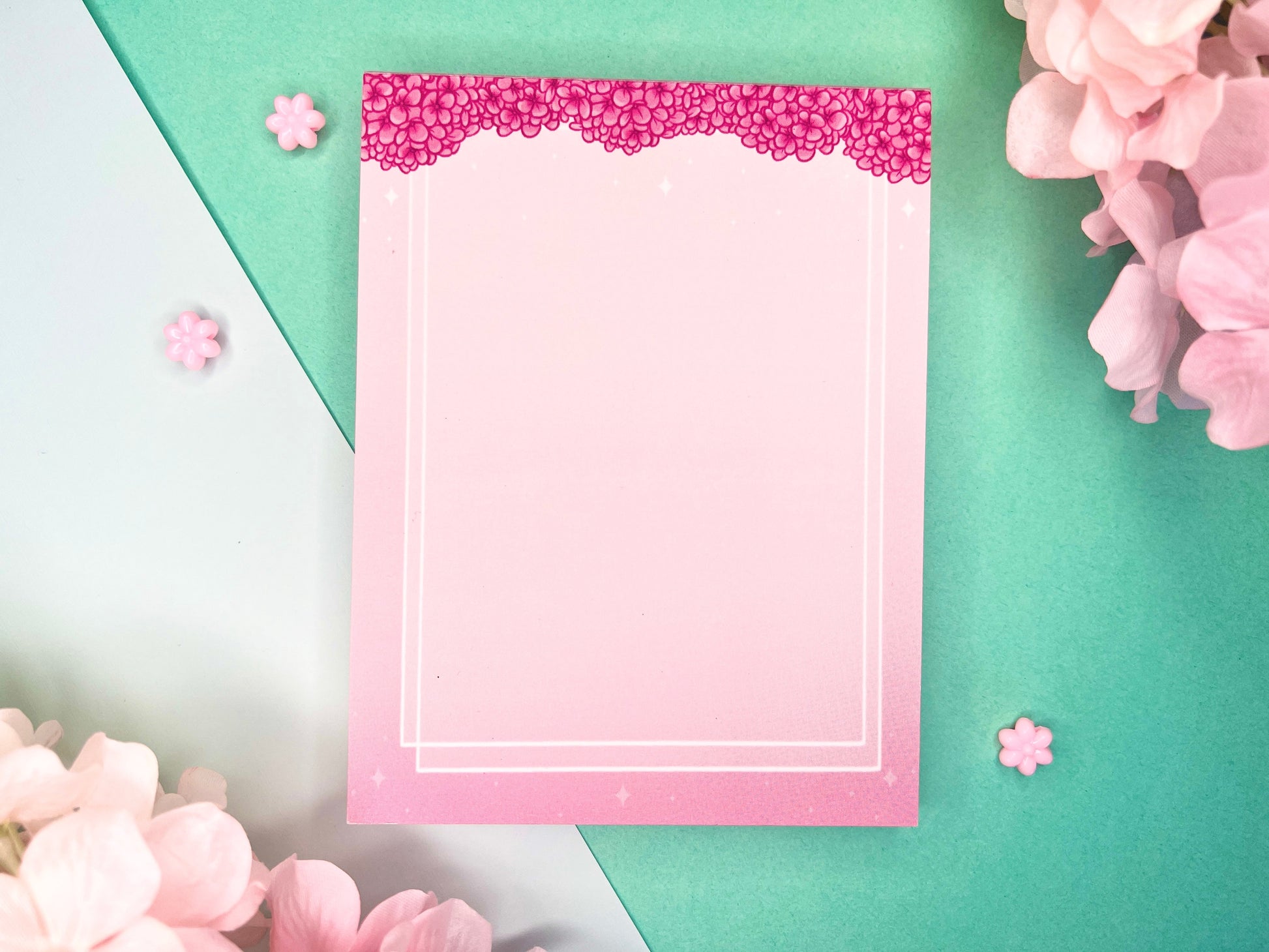 Pink notepad with pink hydrangea flowers bordering the top and a double white border inset from the sides and bottom.