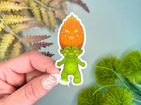 A green retro hair creature with orange hair made to look like a jack o' lantern.