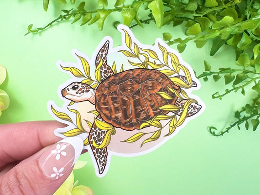 Vinyl sticker of a brown sea turtle swimming through seaweed with a matte mirror finish, 2.4 x 2.8 inches