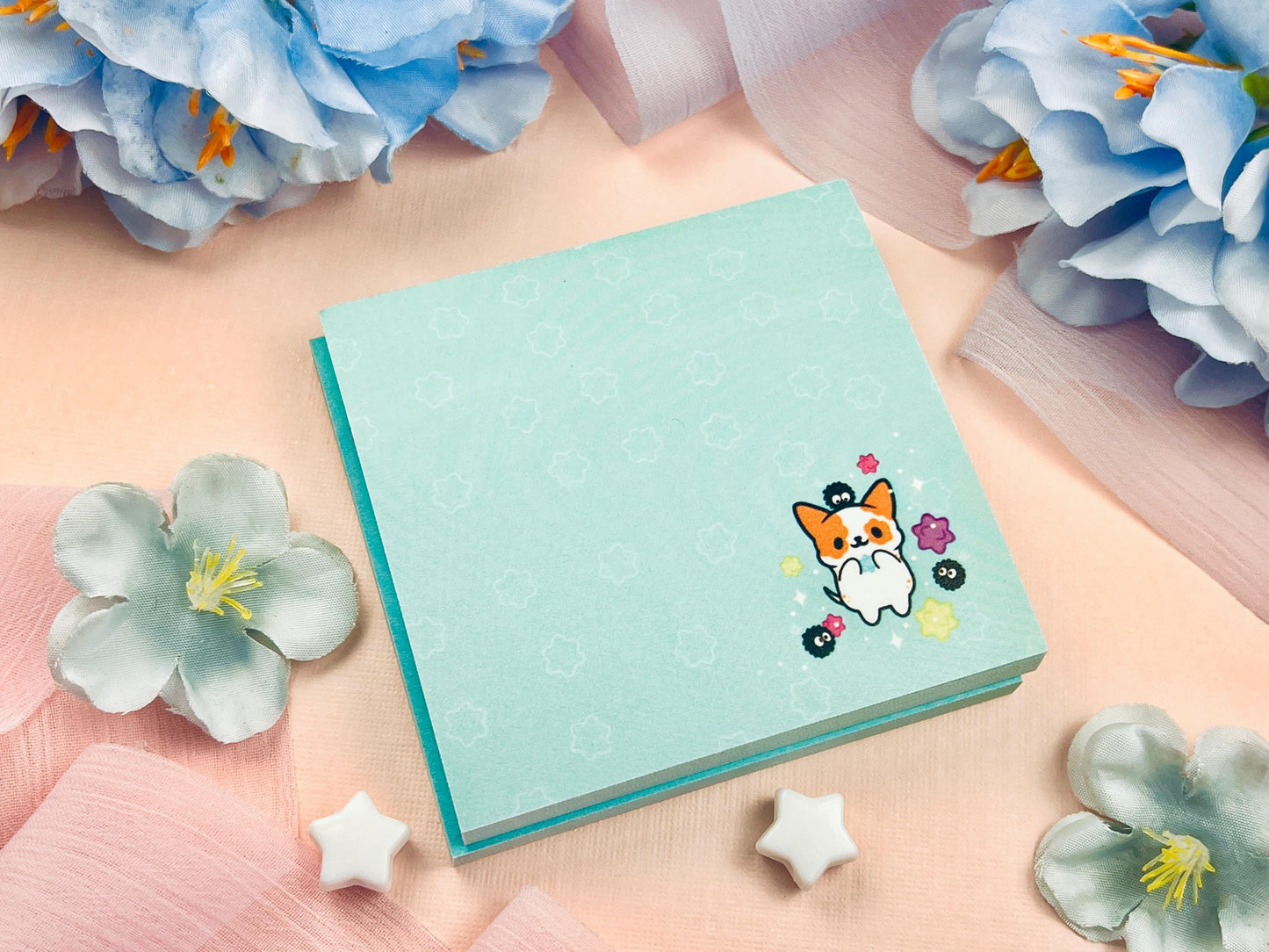 Blue sticky notes with an illustration of a cute dog playing with soot sprites and rainbow konpieto and has a konpieto patterned background.
