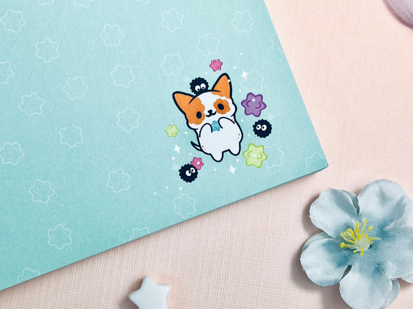 Blue sticky notes with an illustration of a cute dog playing with soot sprites and rainbow konpieto and has a konpieto patterned background.