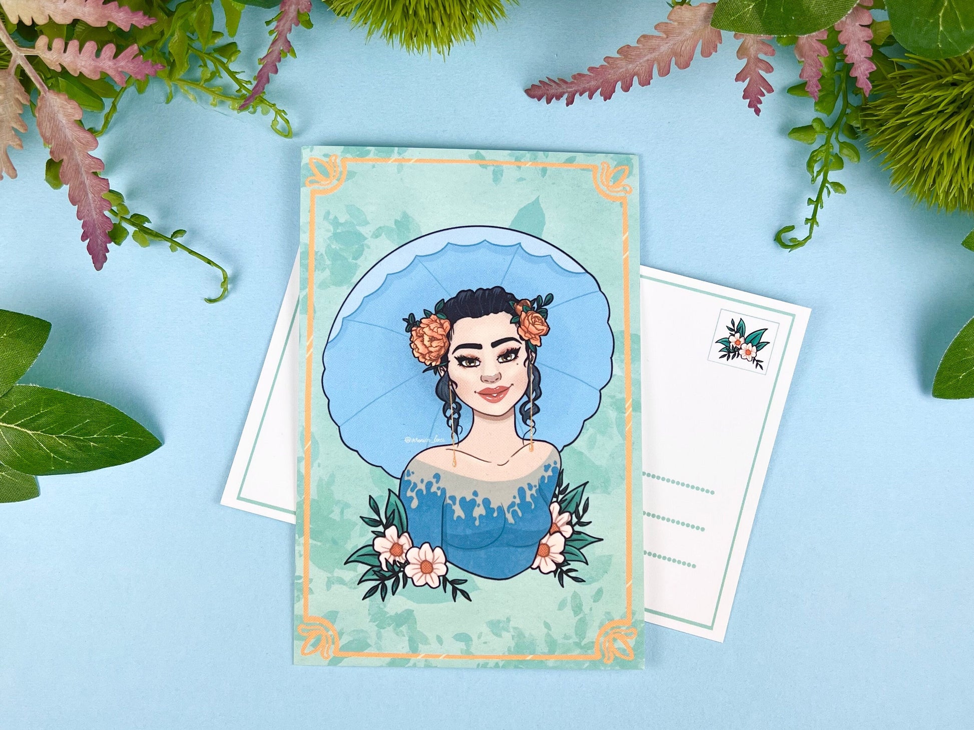 Illustrated card with a woman's portrait holding an umbrella on a blue polka dot background with orange and white flowers.