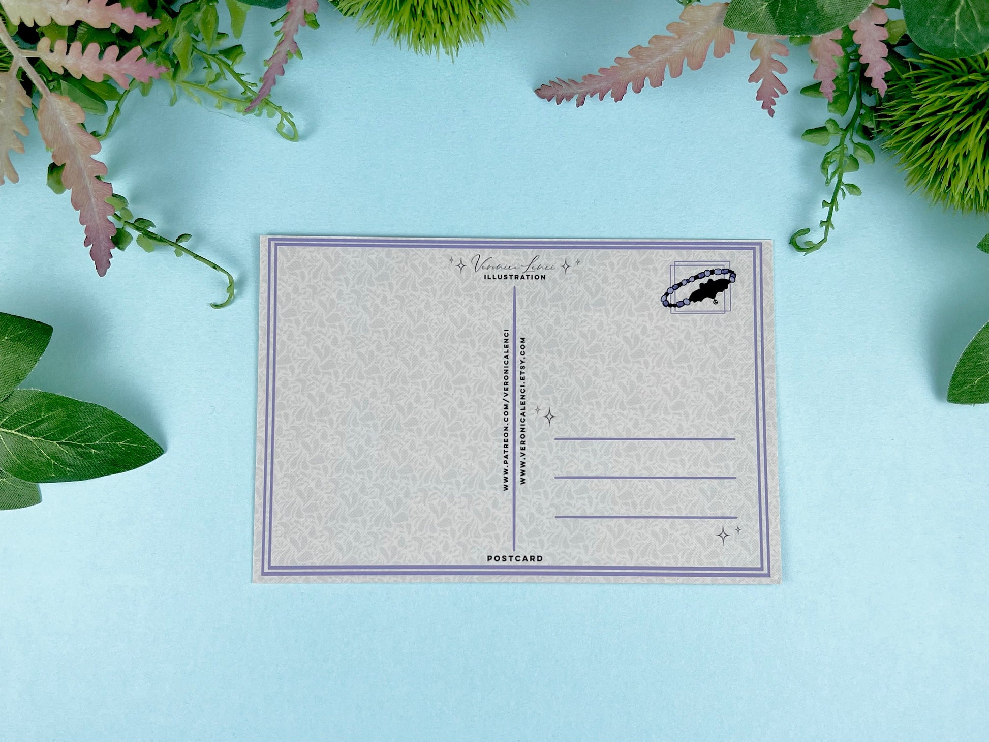 Back of the postcard with a line down the middle, lines on the right side for and address, and a cute bat bracelet illustration where the stamp would go. 