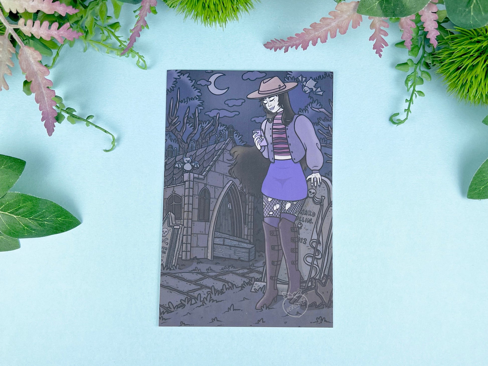 Gothic-style illustration of a vampire in a hat and skirt with a phone on a dark blue/purple background with among gravestones and crypts. 